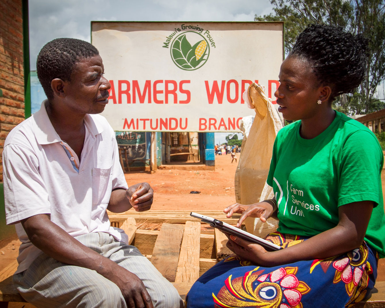 An FSU extension worker interviews a farmer outside one of the Farmer World shops
